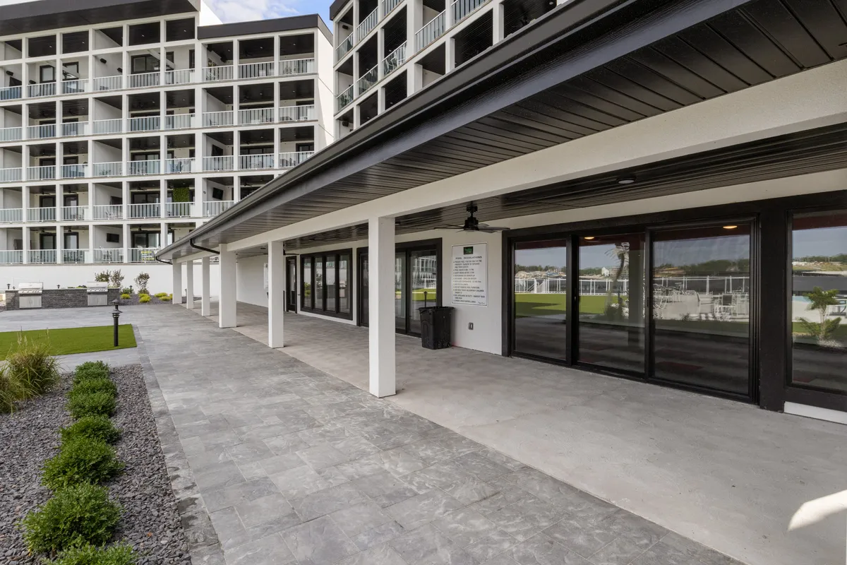 A spacious outdoor patio featuring large windows and modern architecture. The patio is designed for relaxation and social gatherings, with ample room for seating and unobstructed views perfect for enjoying morning coffee or sunset cocktails. The sleek, contemporary aesthetic reflects upscale living.