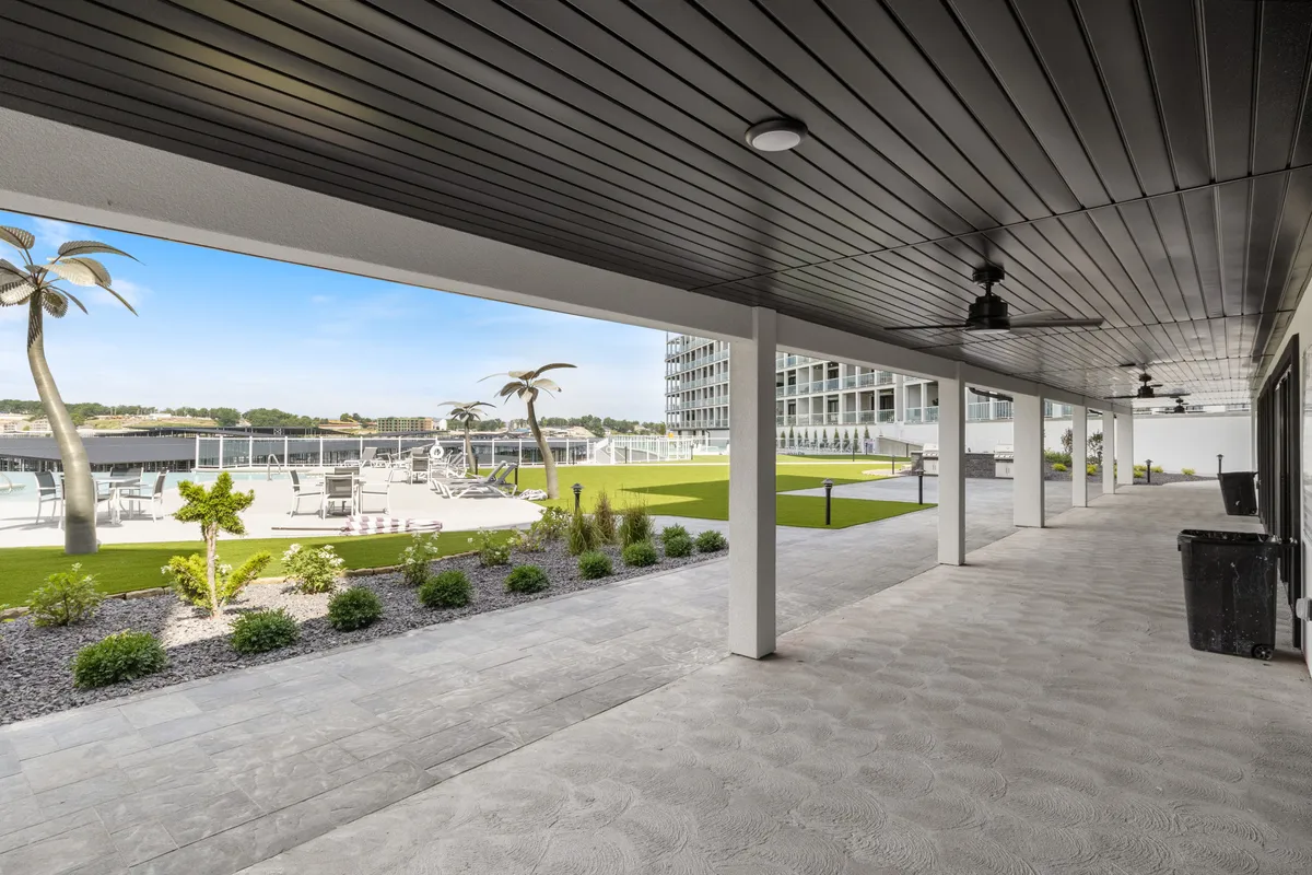 A sparkling swimming pool surrounded by inviting lounge chairs and bordered by a lush green lawn and palm trees. The mood is relaxed and rejuvenating, offering ample space for sunbathing and outdoor gatherings, with the pool being a central hub for guests to enjoy.
