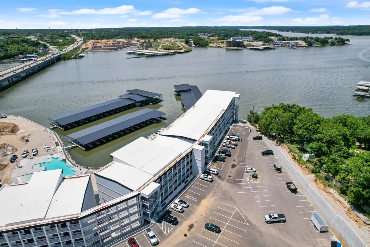 A panoramic exterior scene showcasing the waterfront, parking lot with ample spaces, visible boat docks, and architectural features of the building. The tranquil mood invites relaxation, boating, fishing, and scenic strolls along the shore.