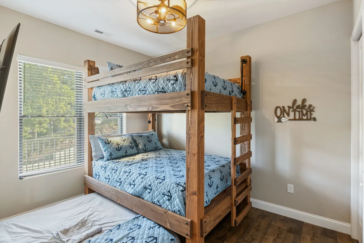 A playful bunkroom designed for group stays, featuring multiple bunk beds with colorful, quilted bedding and cheerful wall decor. The layout is spacious and welcoming, ideal for kids or friends to share laughter and stories into the night.